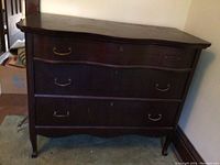 Front view of the dark wooden chest showing three drawers with vintage metal handles, surface scratches and watermarks visible.
