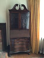 Full frontal view of the vintage wooden secretary desk with glass doors on upper cabinet and four lower drawers.