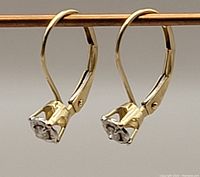 Close view of the earrings highlighting the diamond setting and lever-back detail in gold.