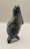 Front-right angle view of a dark stone Inuit standing seal carving showing natural veining and smooth surface.