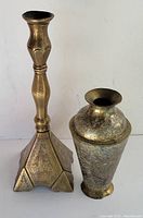 Photo showing side view of the engraved Middle Eastern brass vase and candlestick side by side on white background