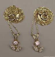 Two 10kt gold chains with flower pendants laid out on neutral background