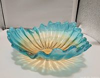 Angled front view of green and yellow scalloped glass bowl showing colors and ruffled edge.