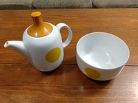 Photo showing white Rosenthal tea pot and bowl with mustard yellow dot pattern on wooden table.