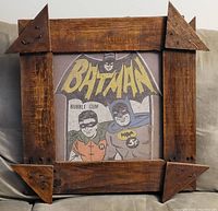 Framed vintage Batman t-shirt showing Batman and Robin in comic style with the word BATMAN and bubble gum price of 5 cents. Rustic wooden frame with nail accents in the corners.