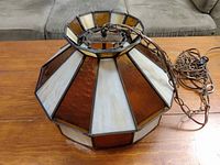 Side view of the chandelier showing the amber and creamy white stained glass panels with chain attached.