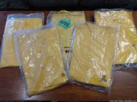 Five yellow rain jackets still in packaging, size medium, laid out on a couch