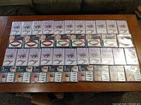 Photo of the full lot on table showing multiple sets of temporary tattoos including eye tattoos, eyeliner tattoos, and lip tattoos in their original packaging.
