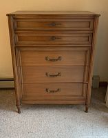 Photo of front view of the tall wooden dresser showing five drawers and metal handles