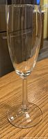 Close-up of a single clear champagne flute style cocktail glass with long stem and rounded bowl.