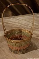 Single small woven basket with a handle, natural material with multicolor stripes