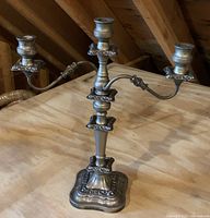 Photo of the ornate three-arm metal candelabra showing detailed floral and scroll design and base