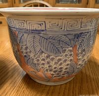 Close-up image showing ceramic planter with blue leafy design and peach accents in glaze.