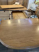 Photo showing the oak dining table with one leaf being added to extend length.