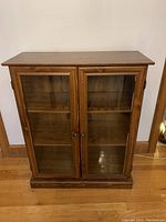 Front view of wooden cabinet with two glass doors showing internal shelves
