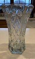 Clear glass vase with distinct starburst and diamond cut pattern, flared top with scalloped edges, shown upright on table.
