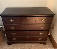 Closed view of the 2 drawer wooden file cabinet with lock, dark wood with brass handles and a few scratches on the surface.