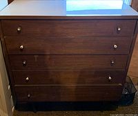 Wooden dresser with four drawers, keyhole pulls, darker wood finish