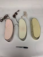 Top view of three headboard lights in pink, white, and cream with embossed decorative designs and cords with plugs.