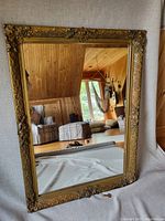 Full view of the large antique mirror showing ornate gold frame and reflection of room.