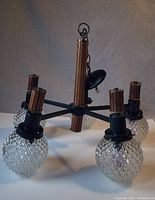 Full view of chandelier showing the five arms with cut glass globes and black metal framing, wood accents on vertical column and sockets.