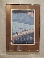 Full view of the framed print showing Hiroshige's rainy bridge scene with figures and river punter.