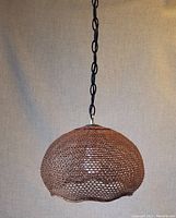 Photo of vintage brown wicker hanging light shown hanging against a beige background