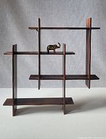 Full view of the multi-level wooden display shelf with geometric open compartments and the brass elephant placed on one shelf