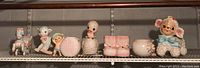 Wide view of all seven ceramic figures lined up on a shelf showing size and color variety