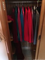 Photo of multiple blazers hanging inside closet. Colors include red, teal, gray, and burgundy. Shows seven blazers total.