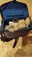 Camera bag opened showing camera inside with accessories and lens cleaning blower bulb