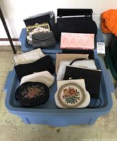 Overall view of collection of assorted purses and handbags in plastic bin showing variety of styles and sizes.