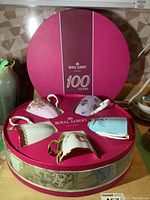 Five Royal Albert decade mugs arranged in original round pink box