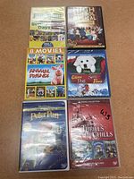 Photo showing 8 DVDs and Blu-Ray cases including Sesame Street, High School Musical, Animal Friends Collection, Santa Paws, Peter Pan, and Disney Thrills and Chills collection.