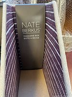 Close-up of one Nate Berkus magazine box showing its modern purple and white diagonal stripe design with a front label holder.
