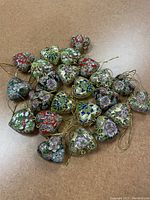 Overview photo displaying all 23 vintage cloisonne-style heart ornaments arranged loosely on a surface, showing variety in colors and patterns.