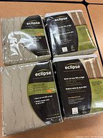 Four new Eclipse Thermalayer blackout curtain panels in original packaging, beige color.