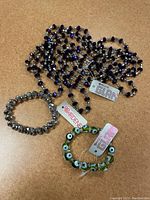 Four bracelets and one necklace with Ardene tags arranged on a brown surface.