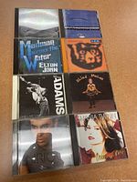 Front view of 8 assorted CDs showing artists Elton John, R.E.M., Bryan Adams, Blind Melon, Shania Twain, and others