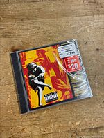 Photo showing the front cover of a Guns N' Roses CD album Appetite for Destruction in original shrink wrap with retail price and promotional stickers intact.