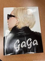 Front cover of Lady Gaga coffee table photo book showing Lady Gaga in profile wearing sunglasses and a leather jacket with 'GaGa' on the back.