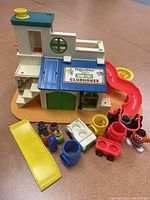 Photo of Fisher Price 1976 Sesame Street Clubhouse with figurines, plastic slides, and accessories arranged around it.
