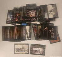 Photo showing numerous Harley-Davidson collectible cards laid out in multiple stacks displaying both fronts and backs.