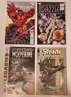 Photo showing four comic books: Avenging Spider-Man variant edition 2, Dazzler #1, Ultimate Comics Wolverine #1, and Spawn #310, all in protective sleeves.