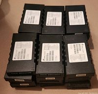 Stacked black Fleet Complete tracker modules with white info labels showing model and ID details.