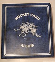 Front cover of the blue hockey card album with white text and drawing of hockey players in action.