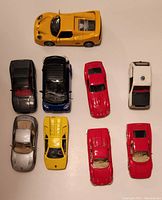 Top view of nine die cast model cars arranged on a flat surface showing various colors and models.