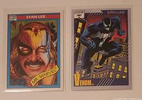 Photo of front sides of two Marvel trading cards: 1990 Stan Lee Mr. Marvel #161 and 1991 Venom #58 Super-Villains, displayed side by side in clear protective sleeves.