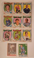 Front view of 11 vintage 1970s OPC hockey cards in protective sleeves, showing player portraits and team logos from Sabres, Flyers, North Stars, Rangers, and St. Louis Blues.