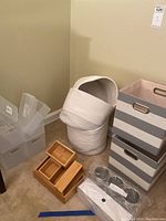 Photo shows round braided baskets, gray striped fabric bins, bamboo organizer, and stackable plastic trays in a corner of a room.